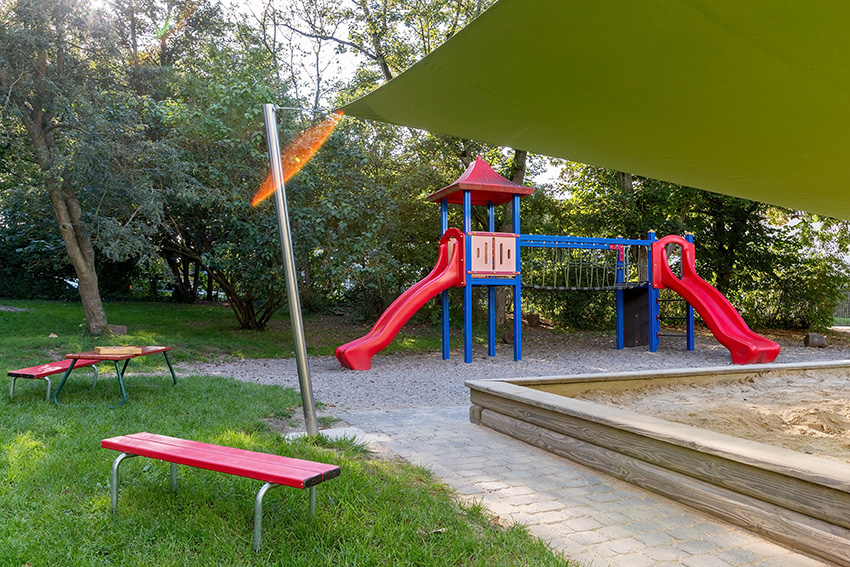 Außenanlage mit großem Sandplatz und Klettergerüst